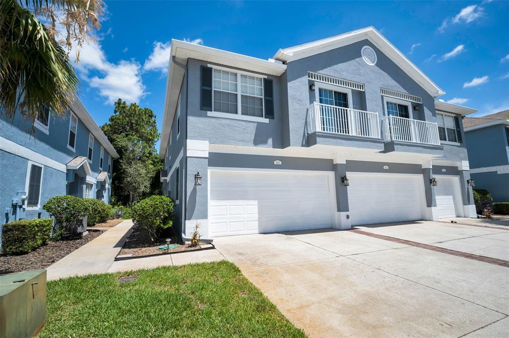A two-story gray townhouse with white trim, a two-car garage, and upper-level balconies — 8525 SHALLOW CREEK, NEW PORT RICHEY, FL