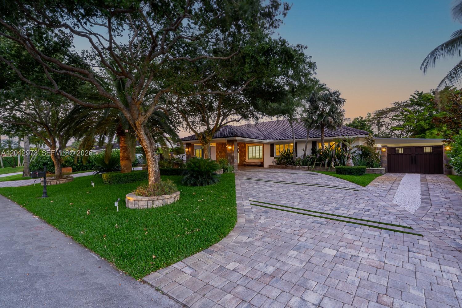 A single-story house with a tiled roof features a paved driveway and mature trees — 10570 SW 56th Ter, Miami FL 33173, MIAMI, FL
