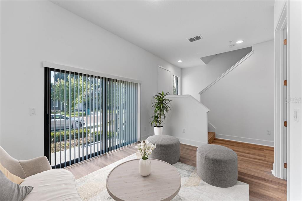 A living room features light wood flooring, a sliding glass door, and a staircase — 42 W HARDING STREET UNIT C, ORLANDO, FL