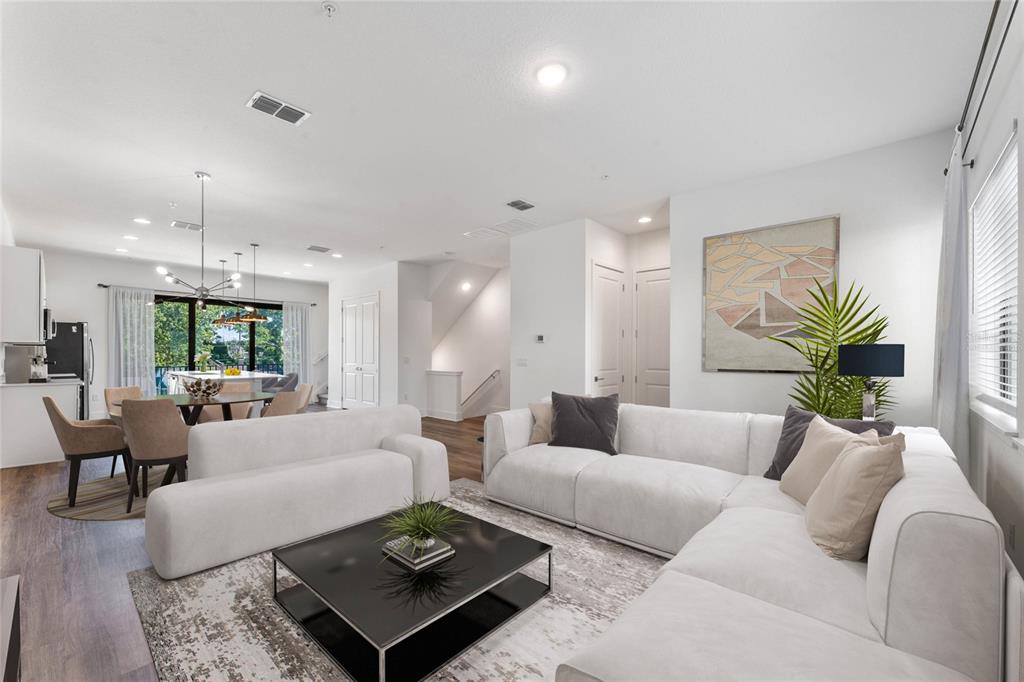 An open-concept living and dining area features white sofas, a black coffee table, and hardwood floors — 42 W HARDING STREET UNIT C, ORLANDO, FL