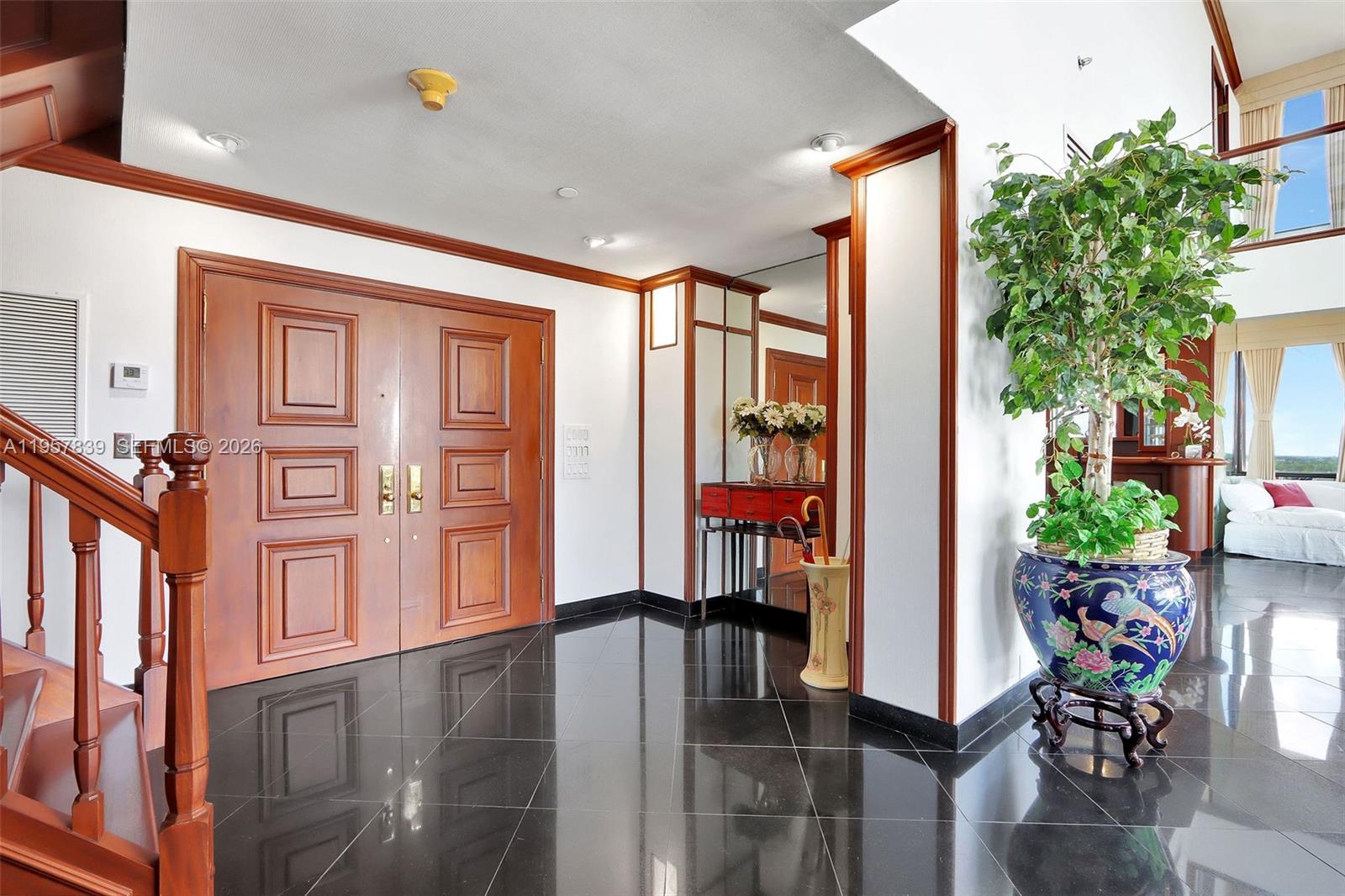An entryway features double wooden doors, black tile flooring, and a large potted plant — 11113 Biscayne Blvd, Miami FL 33181, MIAMI, FL