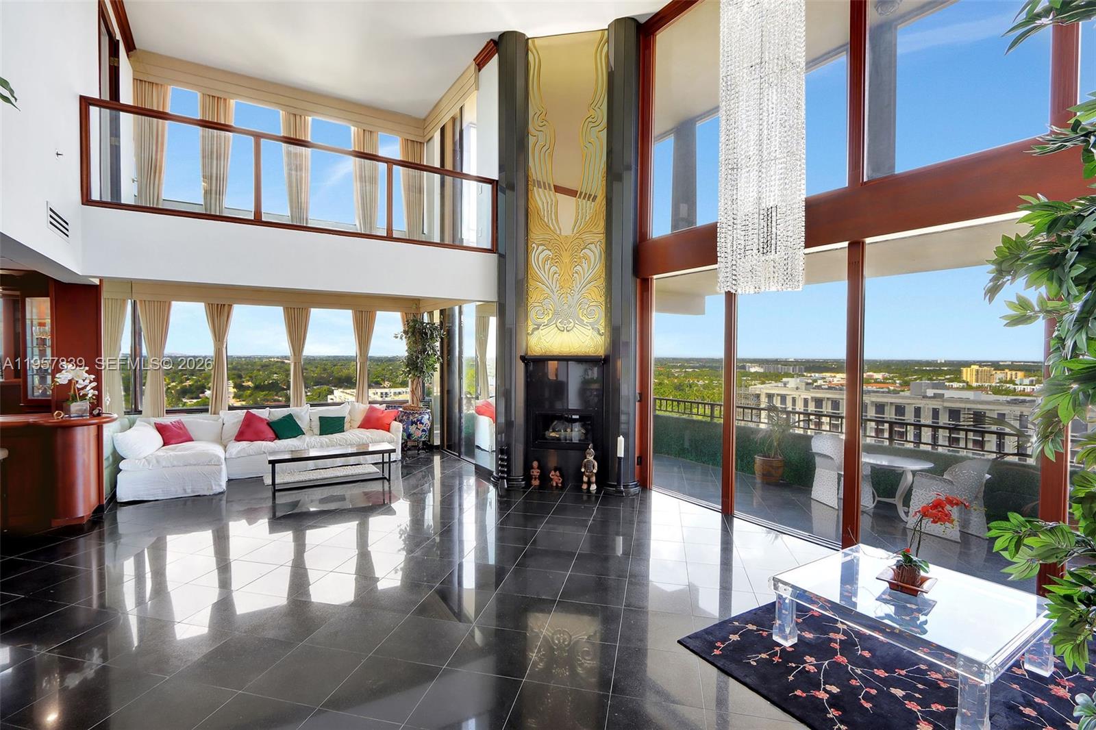 A two-story living room features black tile floors, a tall fireplace, and floor-to-ceiling windows — 11113 Biscayne Blvd, Miami FL 33181, MIAMI, FL