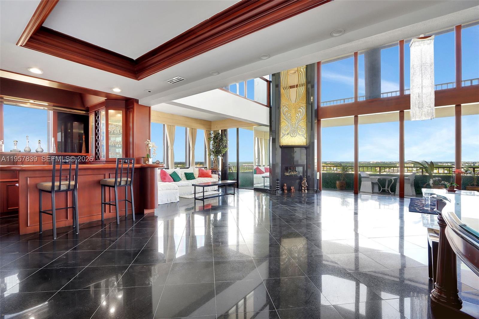 A spacious living area features a built-in bar, black tile flooring, and floor-to-ceiling windows — 11113 Biscayne Blvd, Miami FL 33181, MIAMI, FL