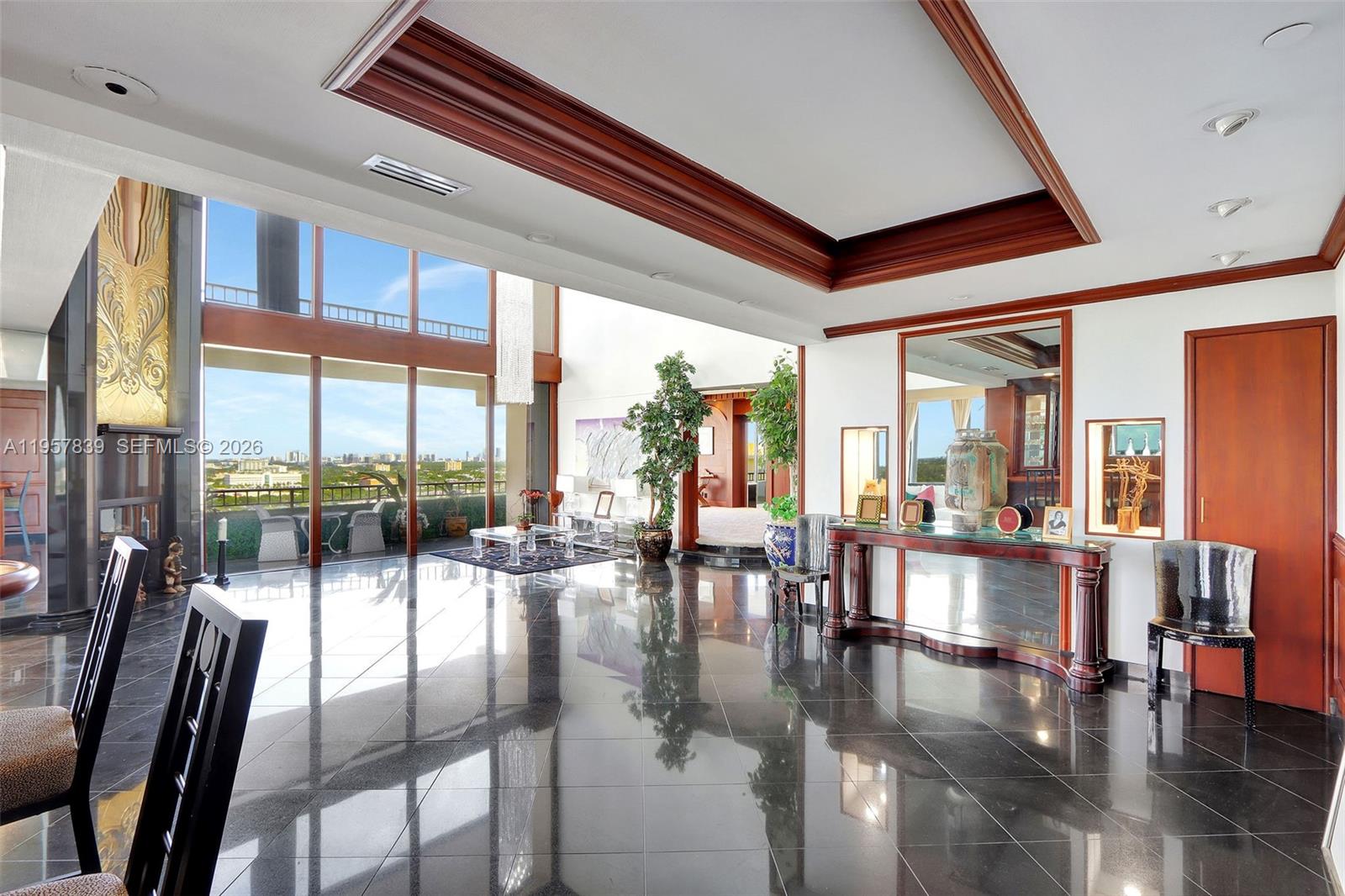A spacious living room features black tile floors, a coffered ceiling, and floor-to-ceiling windows — 11113 Biscayne Blvd, Miami FL 33181, MIAMI, FL