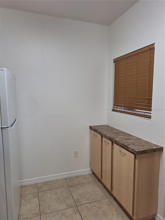 A kitchen features light wood cabinets, white appliances, brown laminate countertops, and a tiled floor — 495 LAS CORTES LANE UNIT 201, ORLANDO, FL