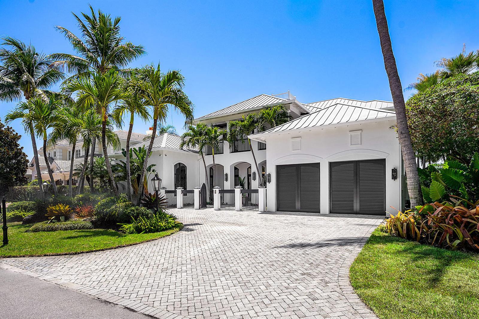 A white two-story house with a metal roof, dark garage doors, and a paved driveway — 1720 Sabal Palm Drive, Boca Raton FL 33432, BOCA RATON, FL