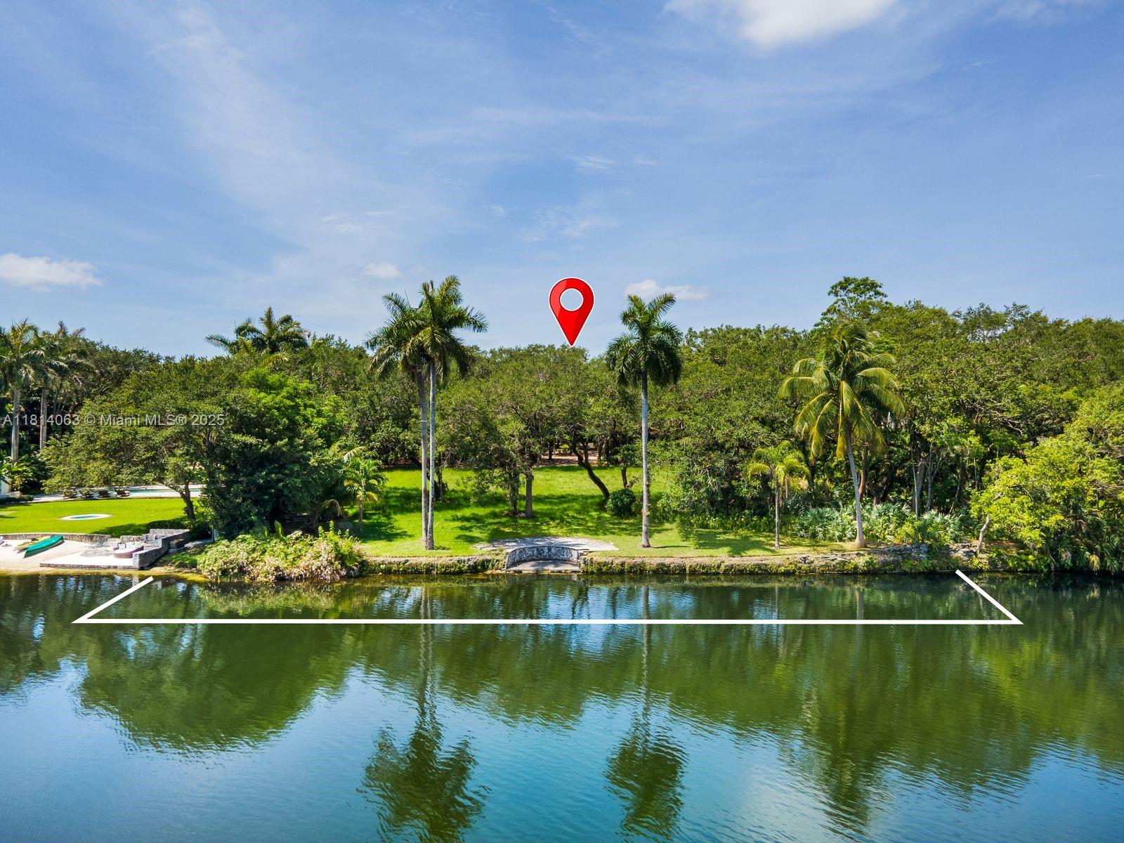 An aerial view shows a grassy waterfront lot with mature trees and a stone bulkhead — 5355 Hammock Dr, Coral Gables FL 33156, CORAL GABLES, FL