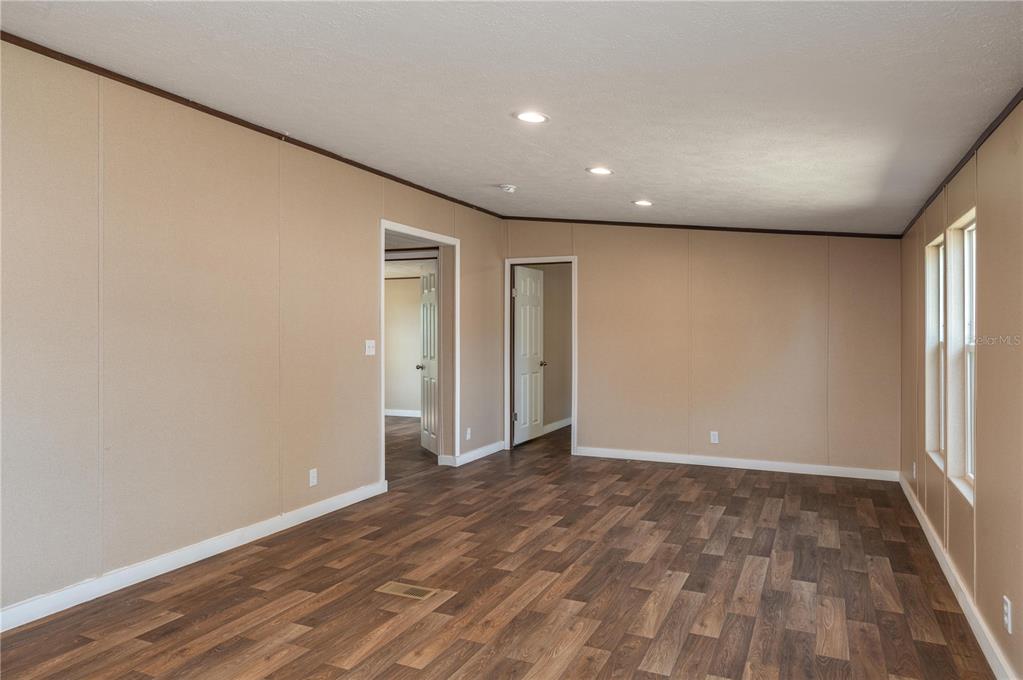 An interior room with tan paneled walls, dark wood-look flooring, and recessed ceiling lighting — 270 OLD BARTOW LAKE WALES, BARTOW, FL