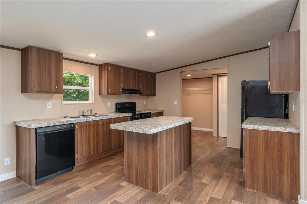 A kitchen with wood-look cabinets, laminate countertops, black appliances, and a central island — 270 OLD BARTOW LAKE WALES, BARTOW, FL