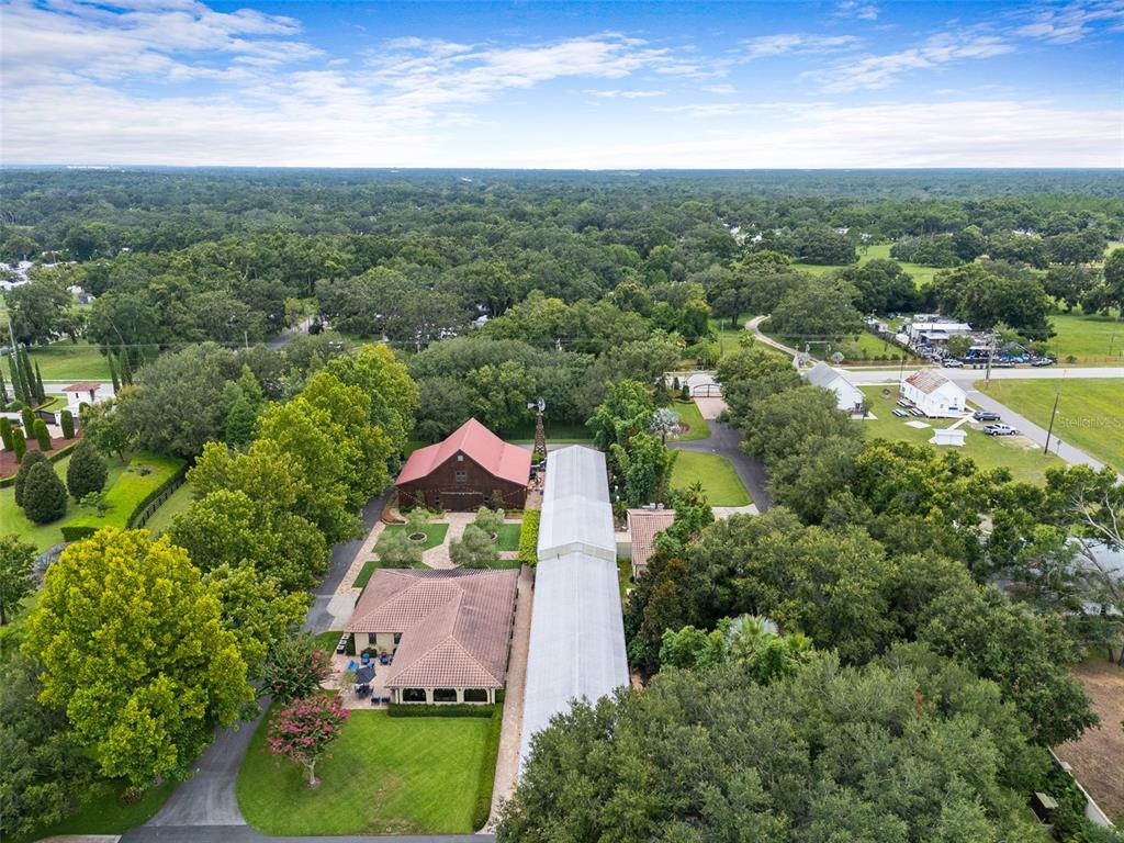 An aerial view shows a house with a red-roofed barn and a long metal structure — 11901 FORT KING HIGHWAY, THONOTOSASSA, FL