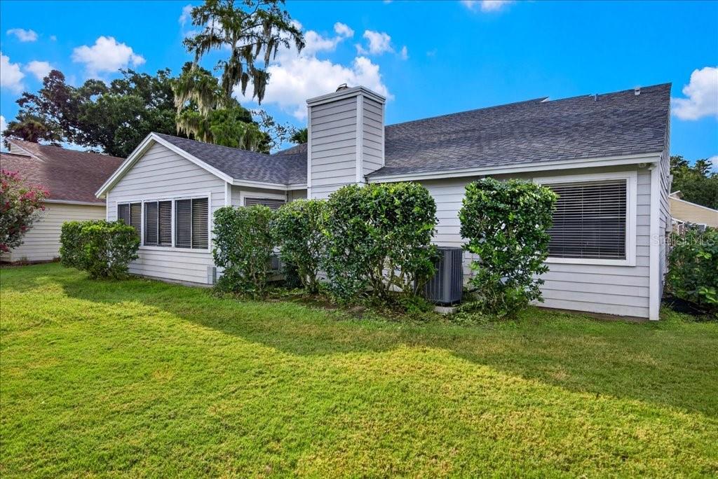 The exterior of a light gray house features a brick chimney and a grassy yard — 112 ALBATROSS WAY, DAYTONA BEACH, FL