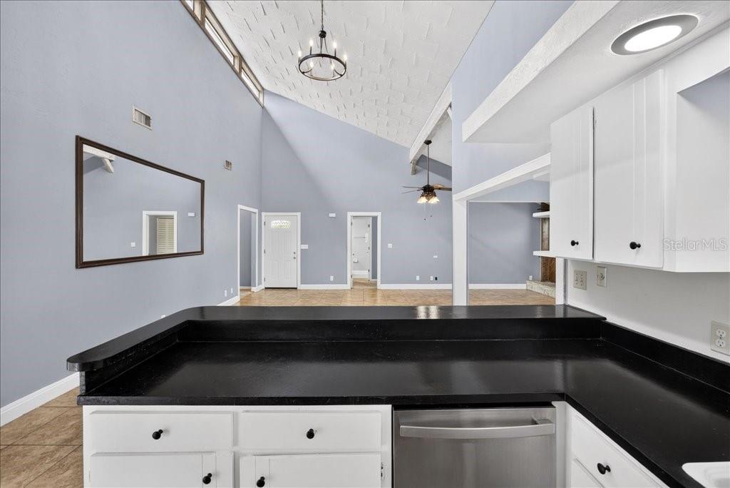 A kitchen with white cabinets, black countertops, stainless steel appliances, and tile flooring — 112 ALBATROSS WAY, DAYTONA BEACH, FL