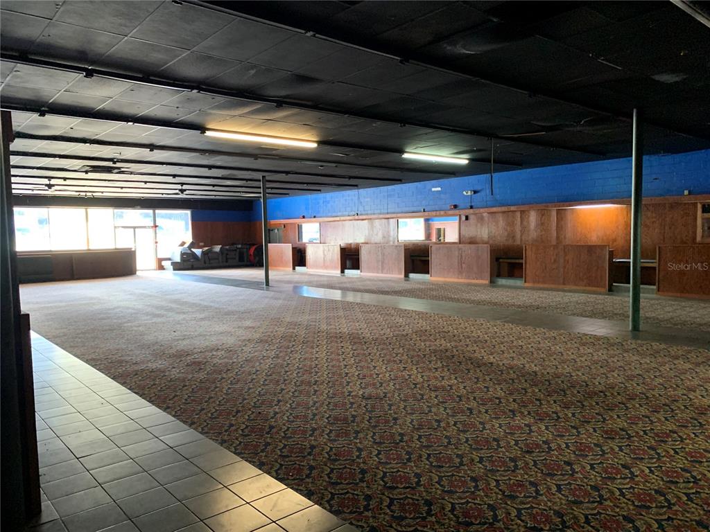 An empty commercial space features patterned carpeting, wood-paneled walls, and a black drop ceiling — 2911 NE JACKSONVILLE ROAD, OCALA, FL
