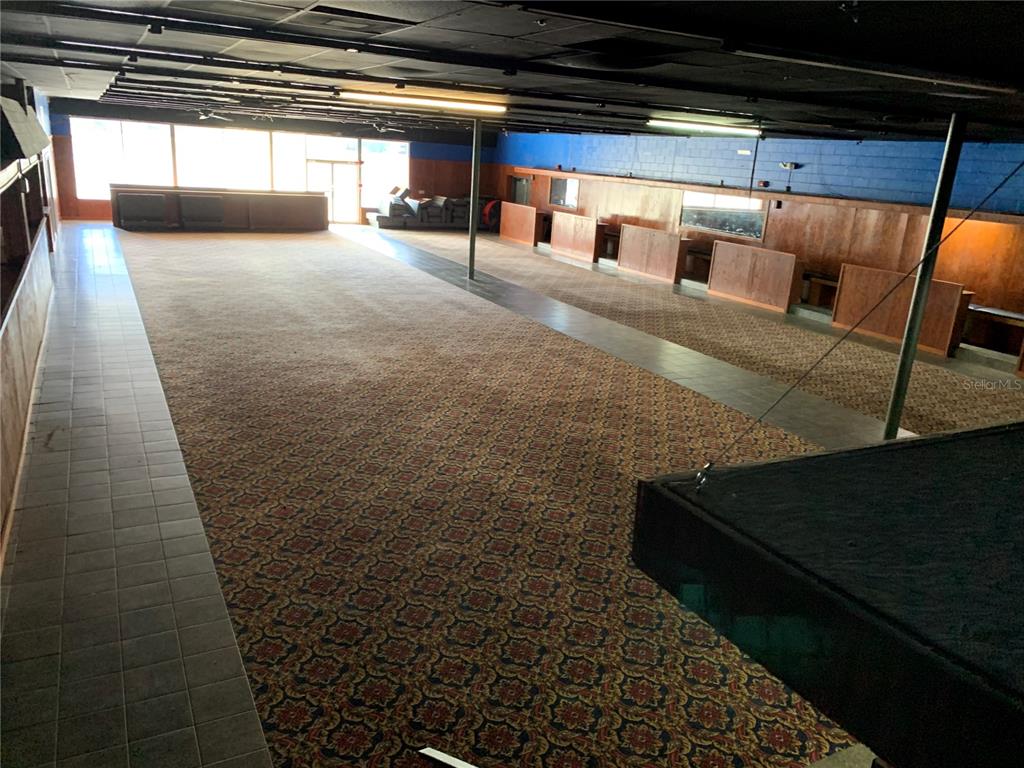 A large, open commercial space features patterned carpeting, wood-paneled booths, and a black drop ceiling — 2911 NE JACKSONVILLE ROAD, OCALA, FL