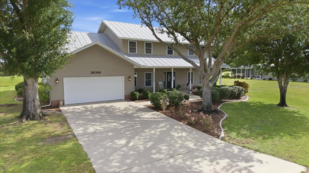 A two-story house with tan siding, a metal roof, and a two-car garage — 26388 HONG KONG ROAD, PUNTA GORDA, FL