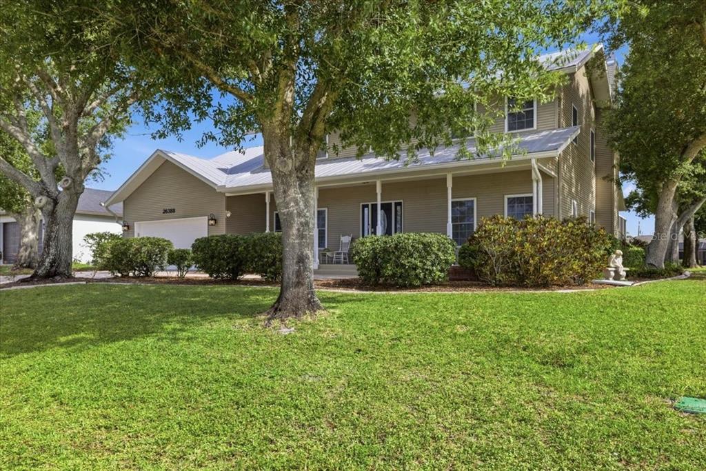A two-story house with beige siding, a metal roof, and a front porch — 26388 HONG KONG ROAD, PUNTA GORDA, FL