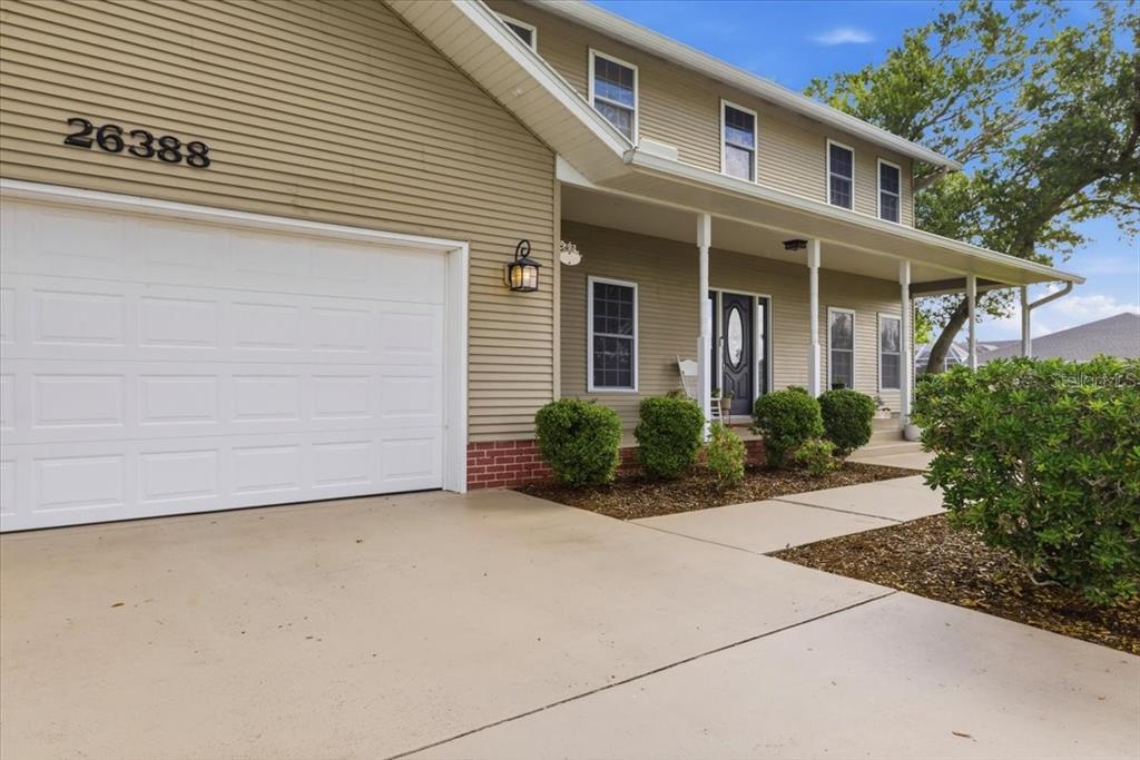 A two-story house with tan siding, a white garage door, and a covered front porch — 26388 HONG KONG ROAD, PUNTA GORDA, FL