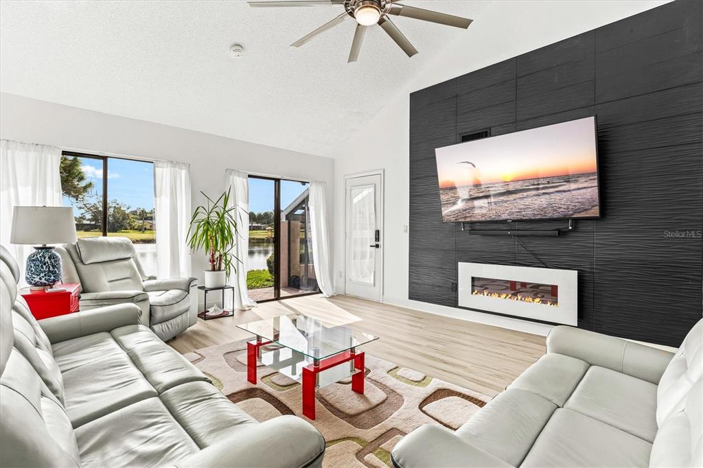 A living room features a black accent wall with a mounted television and electric fireplace — 2453 CRISPIN COURT UNIT F4, SARASOTA, FL