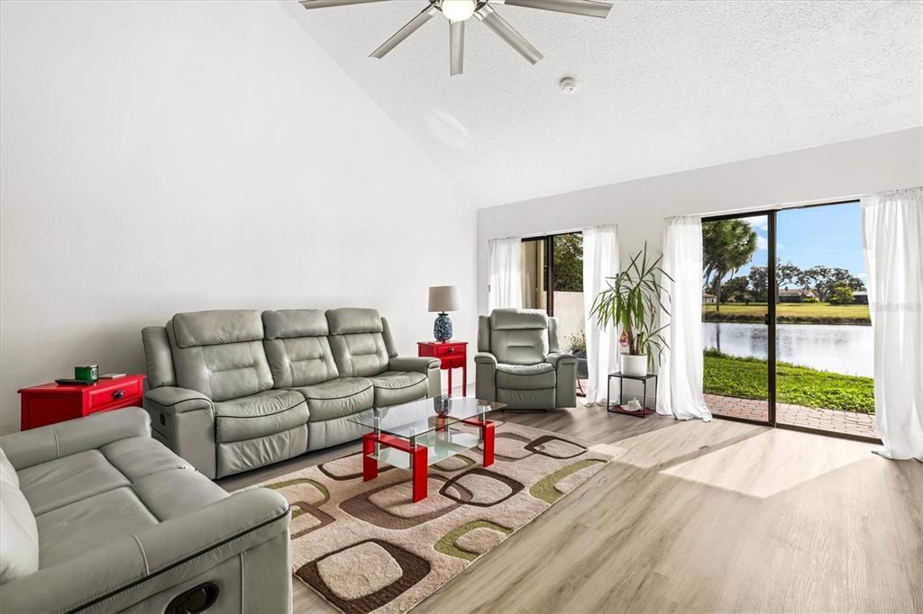 A living room features grey leather furniture, a glass coffee table, and sliding glass doors — 2453 CRISPIN COURT UNIT F4, SARASOTA, FL