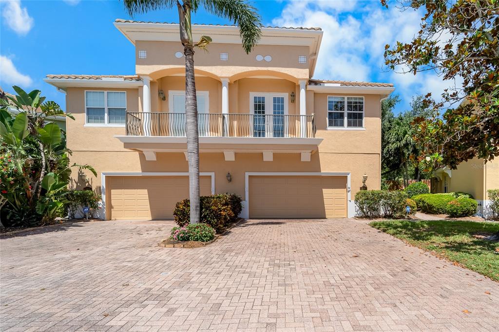 A two-story tan stucco house features a paved driveway, two garage doors, and a balcony — 191 BANYAN BAY DRIVE, ST PETERSBURG, FL