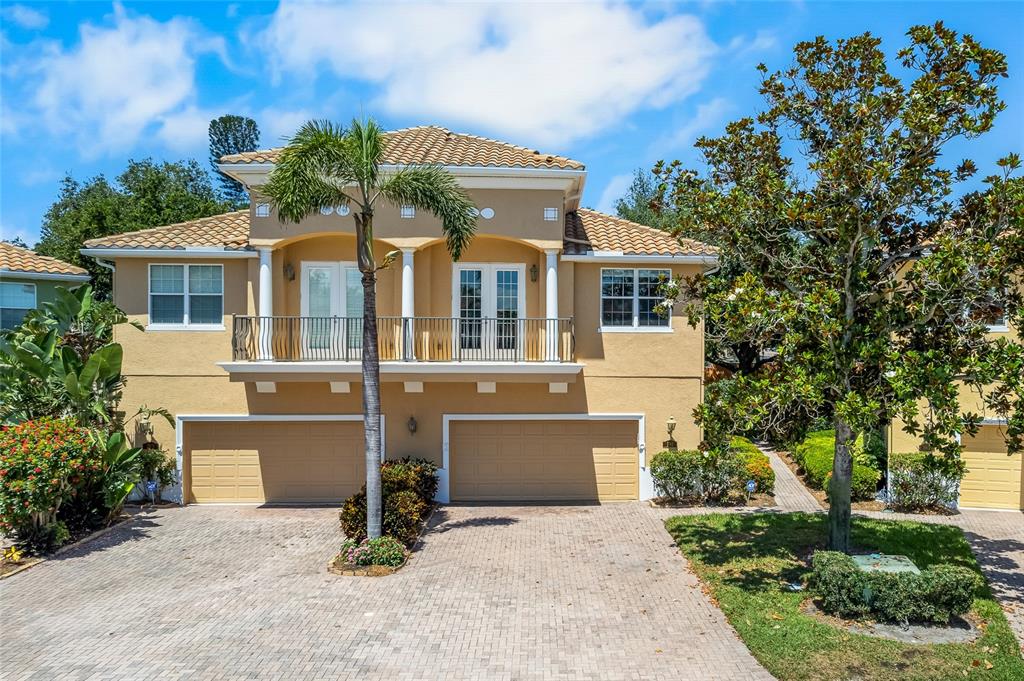 A two-story tan house features a two-car garage, a balcony, and a paved driveway — 191 BANYAN BAY DRIVE, ST PETERSBURG, FL