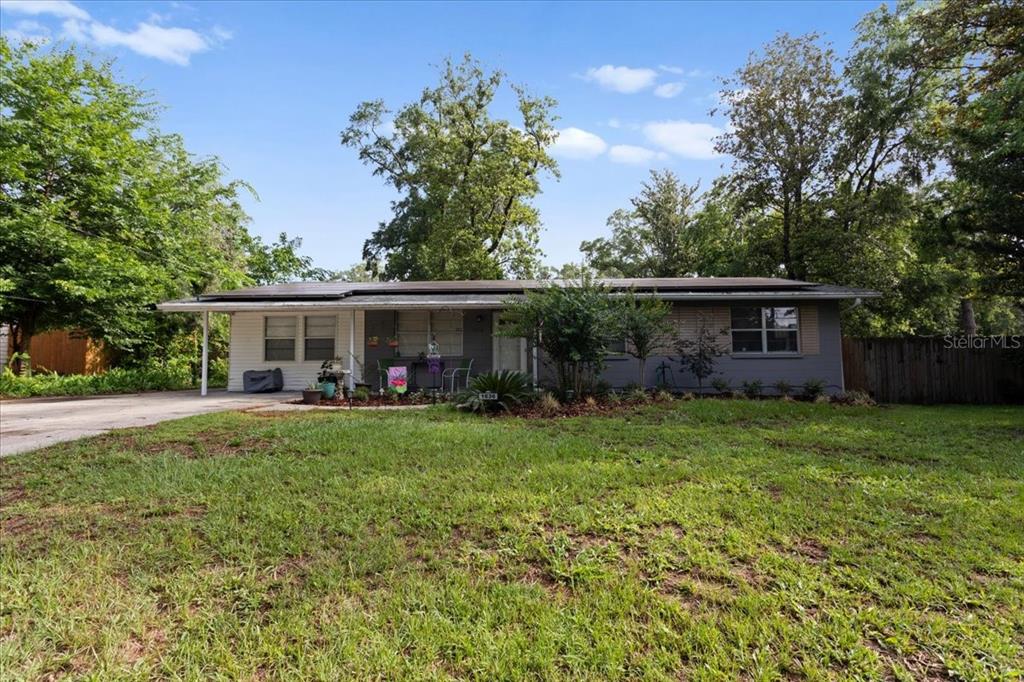 A single-story house with a gray exterior, a flat roof, and a large front lawn — 1636 NW 34TH PLACE, GAINESVILLE, FL