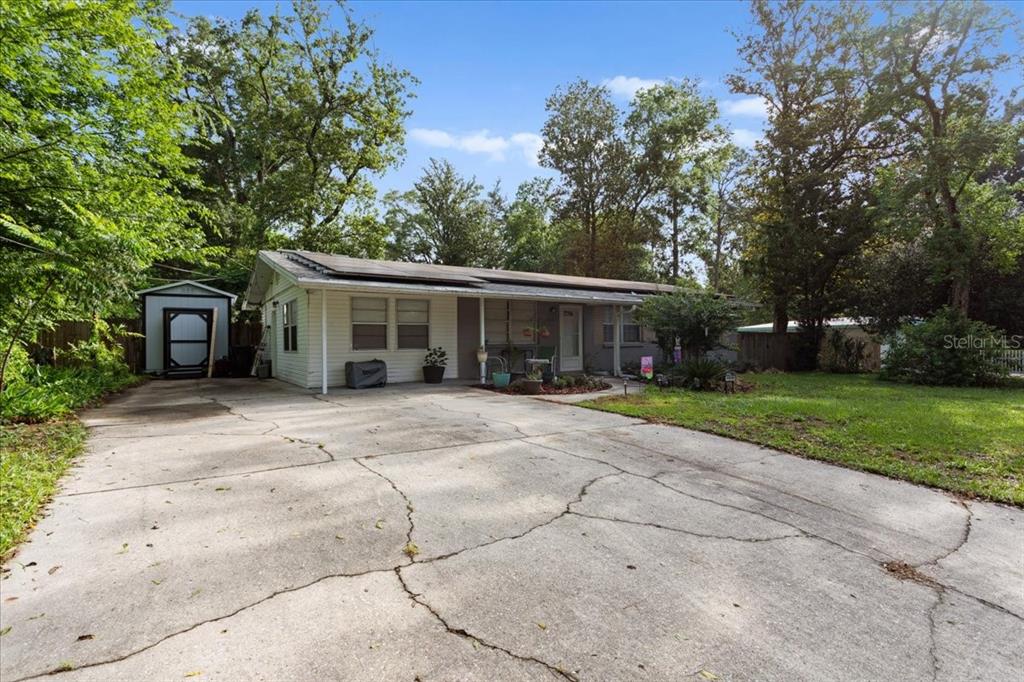 A single-story house with a cracked concrete driveway and a detached shed in the yard — 1636 NW 34TH PLACE, GAINESVILLE, FL