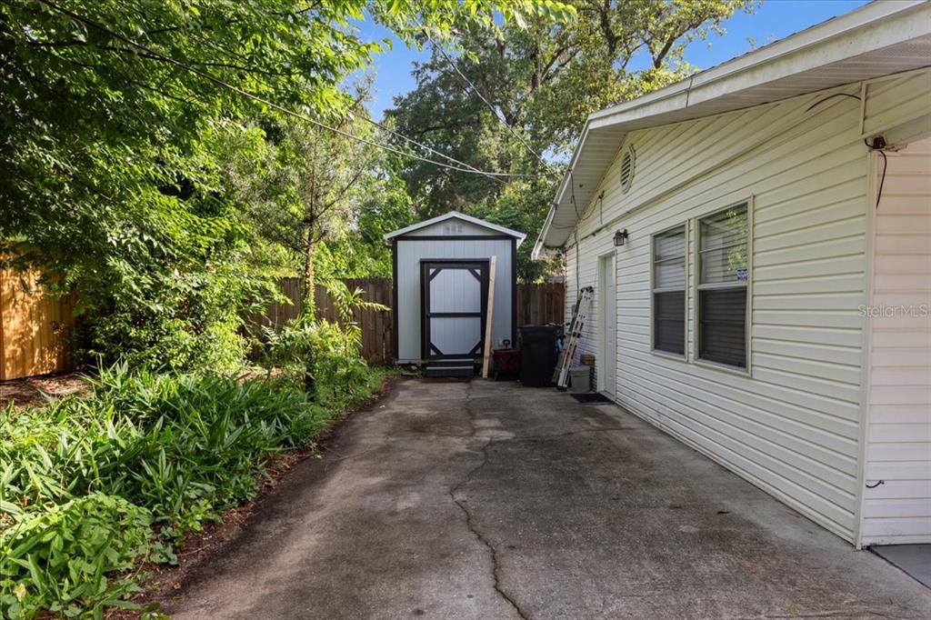 A concrete driveway leads to a small storage shed beside the side of a house — 1636 NW 34TH PLACE, GAINESVILLE, FL