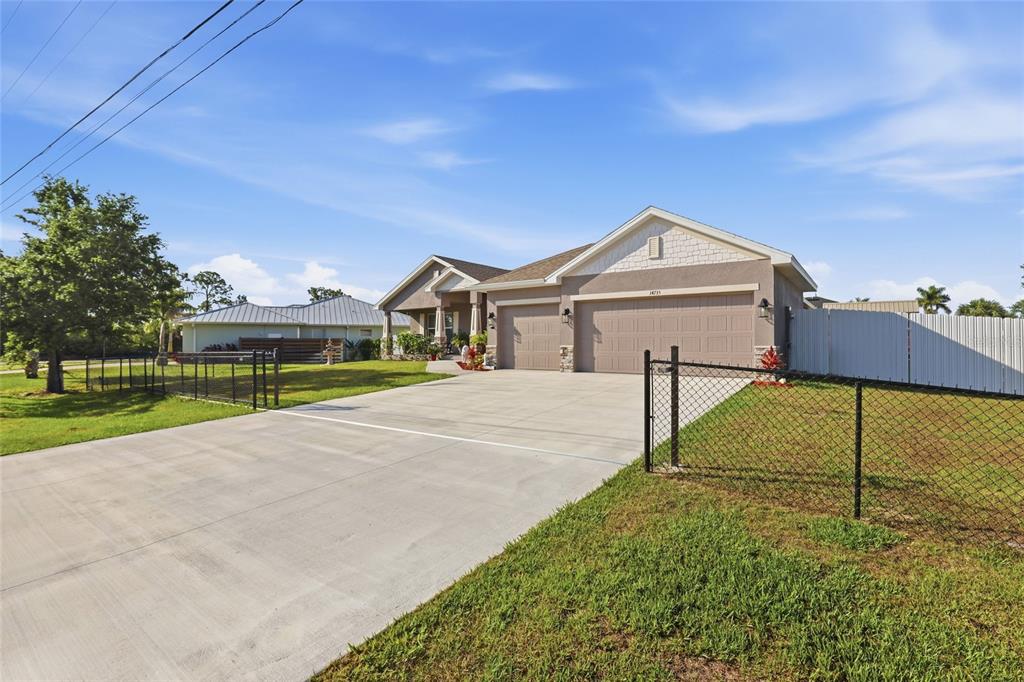 A single-story house with a concrete driveway, three-car garage, and a chain-link fence — 14735 KEYSTONE BOULEVARD, PORT CHARLOTTE, FL