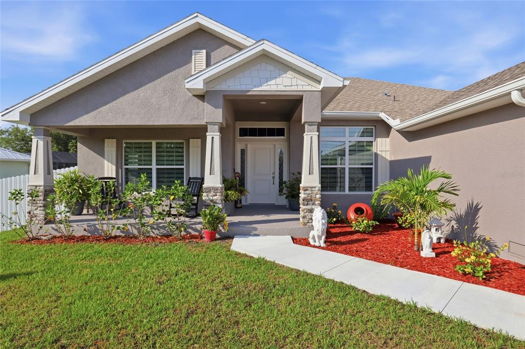 A single-story house with a covered front porch, stone-accented columns, and red mulch landscaping — 14735 KEYSTONE BOULEVARD, PORT CHARLOTTE, FL