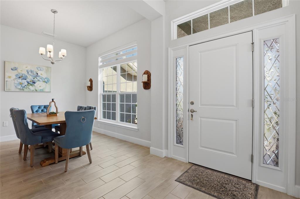 A dining area with blue upholstered chairs sits next to a white front door — 14735 KEYSTONE BOULEVARD, PORT CHARLOTTE, FL