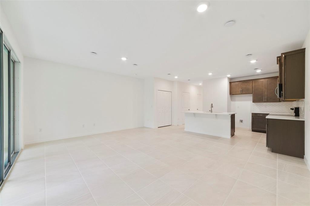 An open-concept kitchen and living area with light tile flooring and dark wood cabinetry — 1661 GREENLEAF WOODS COVE, OVIEDO, FL