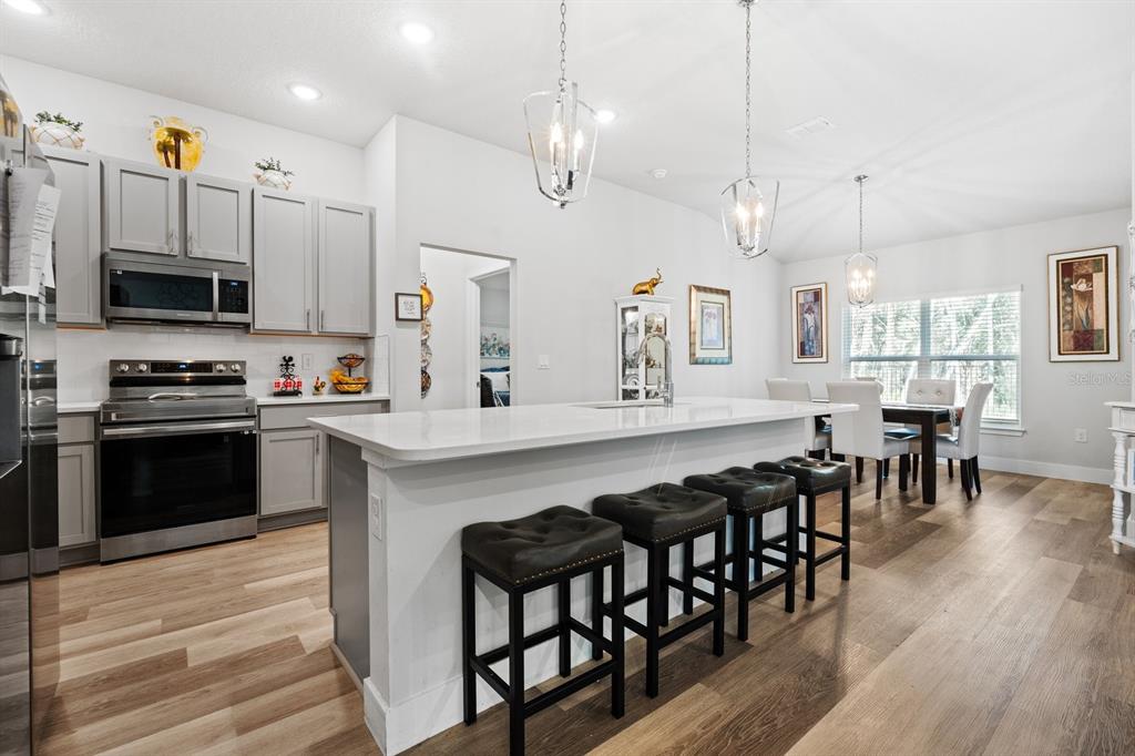 A modern kitchen features gray cabinets, a white quartz island, and wood-look flooring — 18 SEA BOARD COURT, PALM COAST, FL