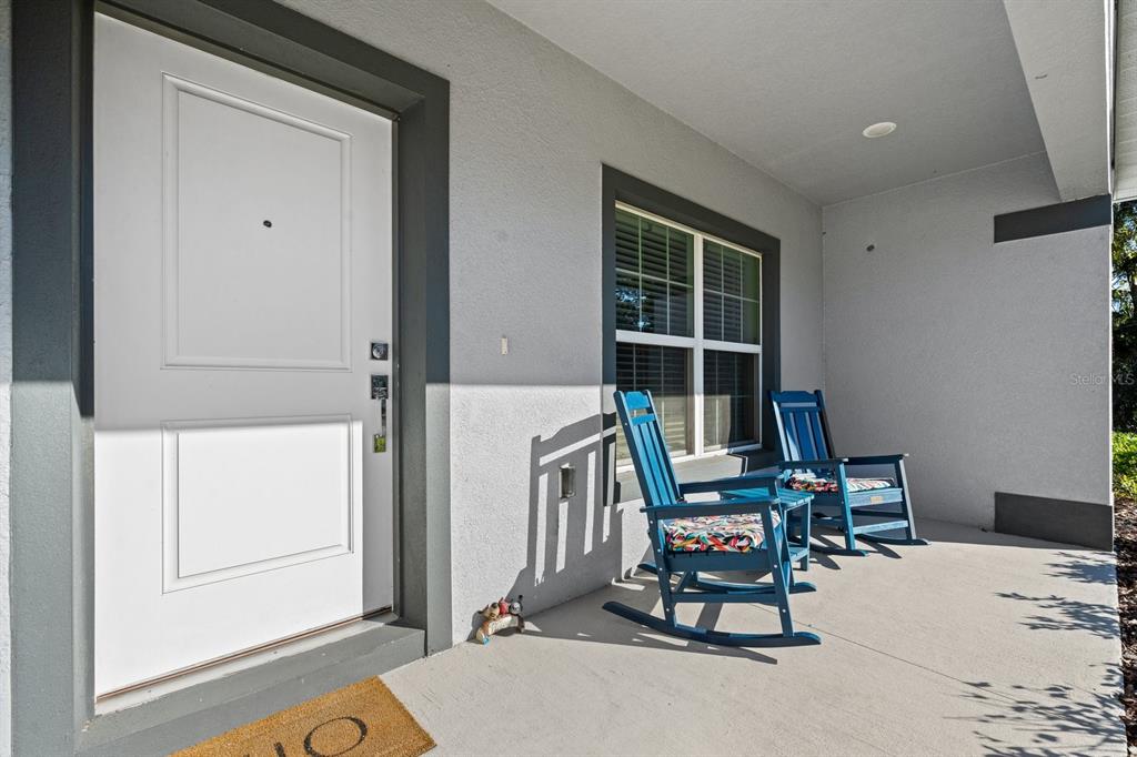 A covered front porch features a white door, a window, and two blue rocking chairs — 18 SEA BOARD COURT, PALM COAST, FL