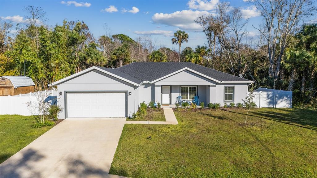A single-story gray house with a two-car garage and a white fence sits on grass — 18 SEA BOARD COURT, PALM COAST, FL