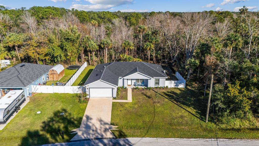 An aerial view shows a single-story house with a gray roof, white siding, and a driveway — 18 SEA BOARD COURT, PALM COAST, FL