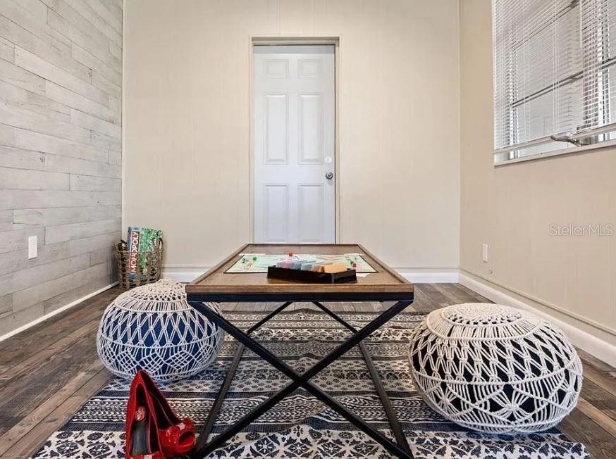 A room features a coffee table with a Monopoly board, two poufs, and wood-look flooring — 4325 ELLIOT AVENUE, TITUSVILLE, FL