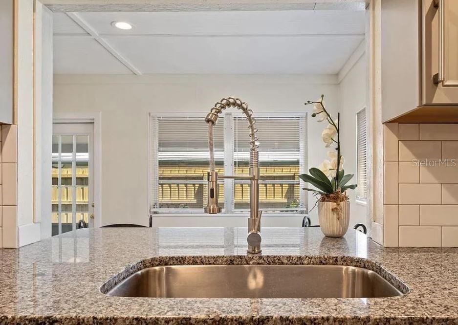 A kitchen sink with a gooseneck faucet sits in a granite countertop before a window — 4325 ELLIOT AVENUE, TITUSVILLE, FL