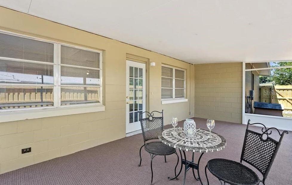 A covered patio with a concrete block wall, carpeted flooring, and a small bistro set — 4325 ELLIOT AVENUE, TITUSVILLE, FL