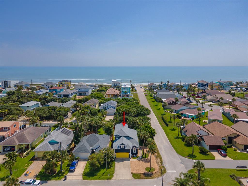 An aerial view shows a coastal neighborhood with a two-story house highlighted by a red arrow — 2733 S DAYTONA AVENUE, FLAGLER BEACH, FL