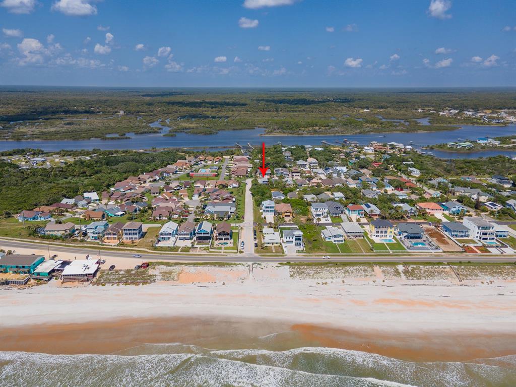 An aerial view shows a beachside neighborhood with a red arrow pointing to a house — 2733 S DAYTONA AVENUE, FLAGLER BEACH, FL