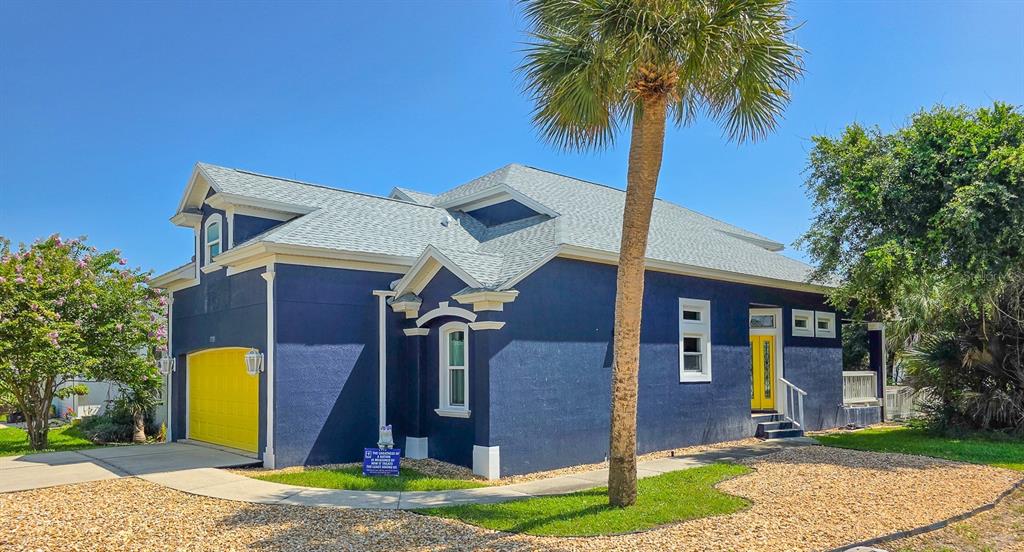 A blue house with a yellow garage door and front door stands under a palm tree — 2733 S DAYTONA AVENUE, FLAGLER BEACH, FL