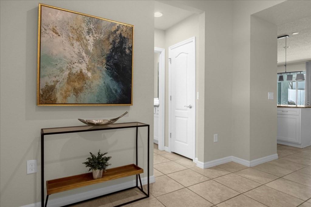 A hallway features tile flooring, a console table with decor, and a large abstract painting — 2413 DUBAI ST, KISSIMMEE, FL