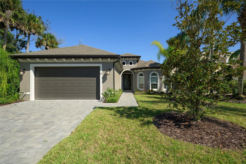 A gray single-story house with a two-car garage, arched windows, and a paved walkway — 27 S RIVERWALK DRIVE, PALM COAST, FL