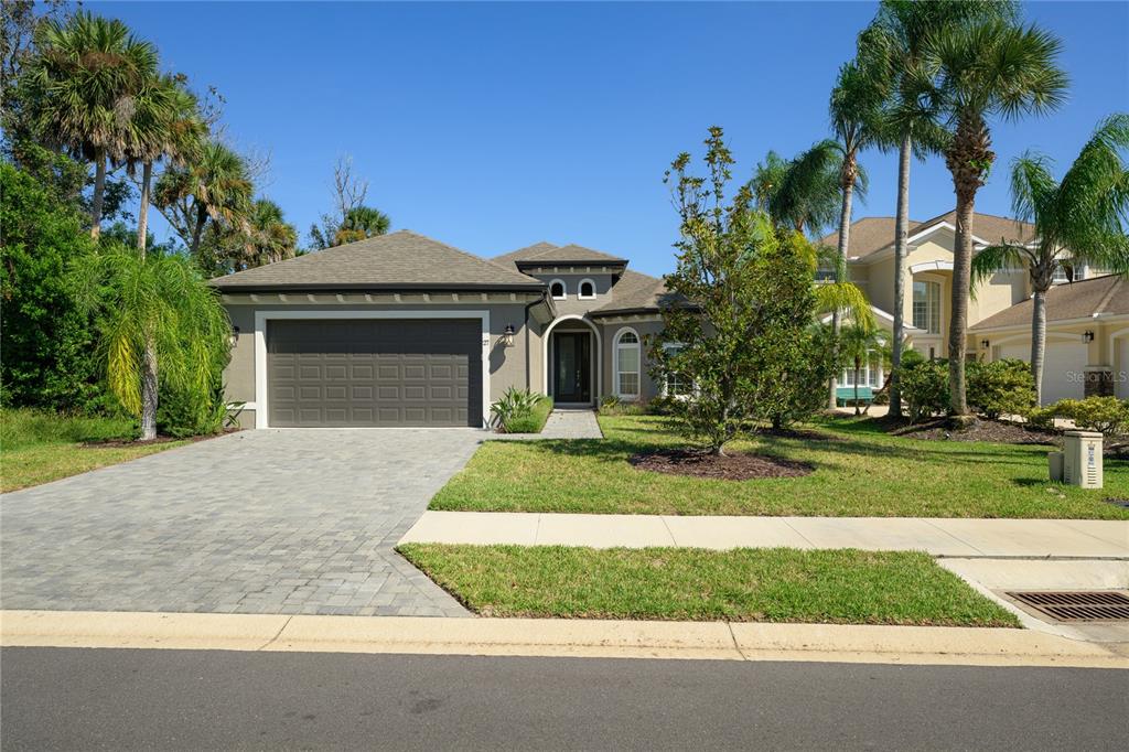 A dark gray front door with a glass panel and sidelight sits in a stucco entryway — 27 S RIVERWALK DRIVE, PALM COAST, FL