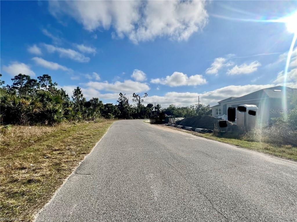 A paved road leads toward a construction site with a portable toilet and house exterior — Lot 30 KISKA ROAD, NORTH PORT, FL