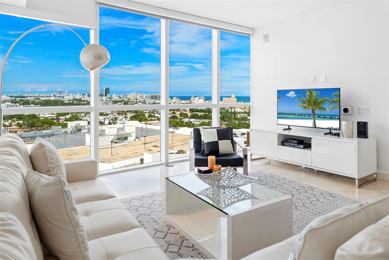 A modern living room features floor-to-ceiling windows with a city and ocean view — 450 Alton Rd # 1708, Miami Beach FL 33139, MIAMI BEACH, FL