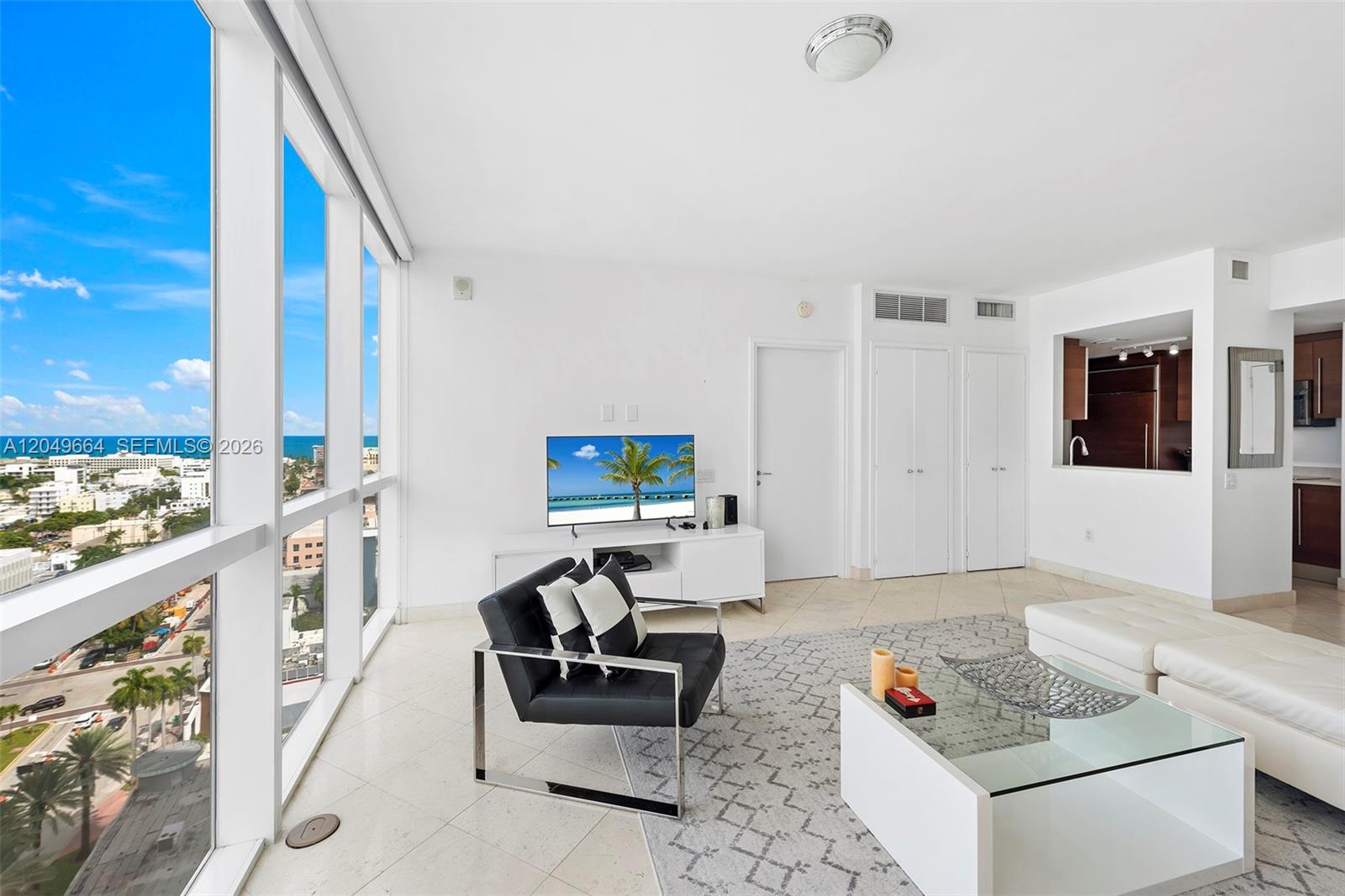 A living room features floor-to-ceiling windows, white tile floors, and a view of the ocean — 450 Alton Rd # 1708, Miami Beach FL 33139, MIAMI BEACH, FL