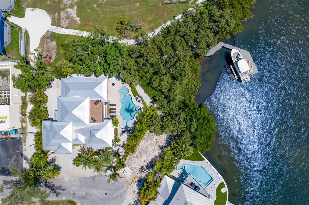 An aerial view shows a waterfront house with a pool, dock, and boat — 220 N HARBOR DRIVE, HOLMES BEACH, FL