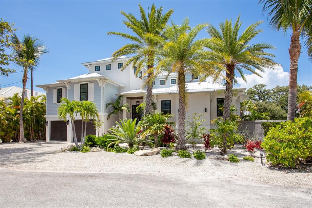 A two-story coastal house with a gravel driveway, palm trees, and a metal roof — 220 N HARBOR DRIVE, HOLMES BEACH, FL